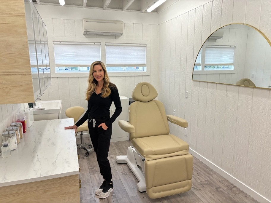 Image of Kindy Lauzon, Owner of Arc Medical Aesthetics, Med Spa in Solana Beach, California standing inside one of the medical suites in her offices.